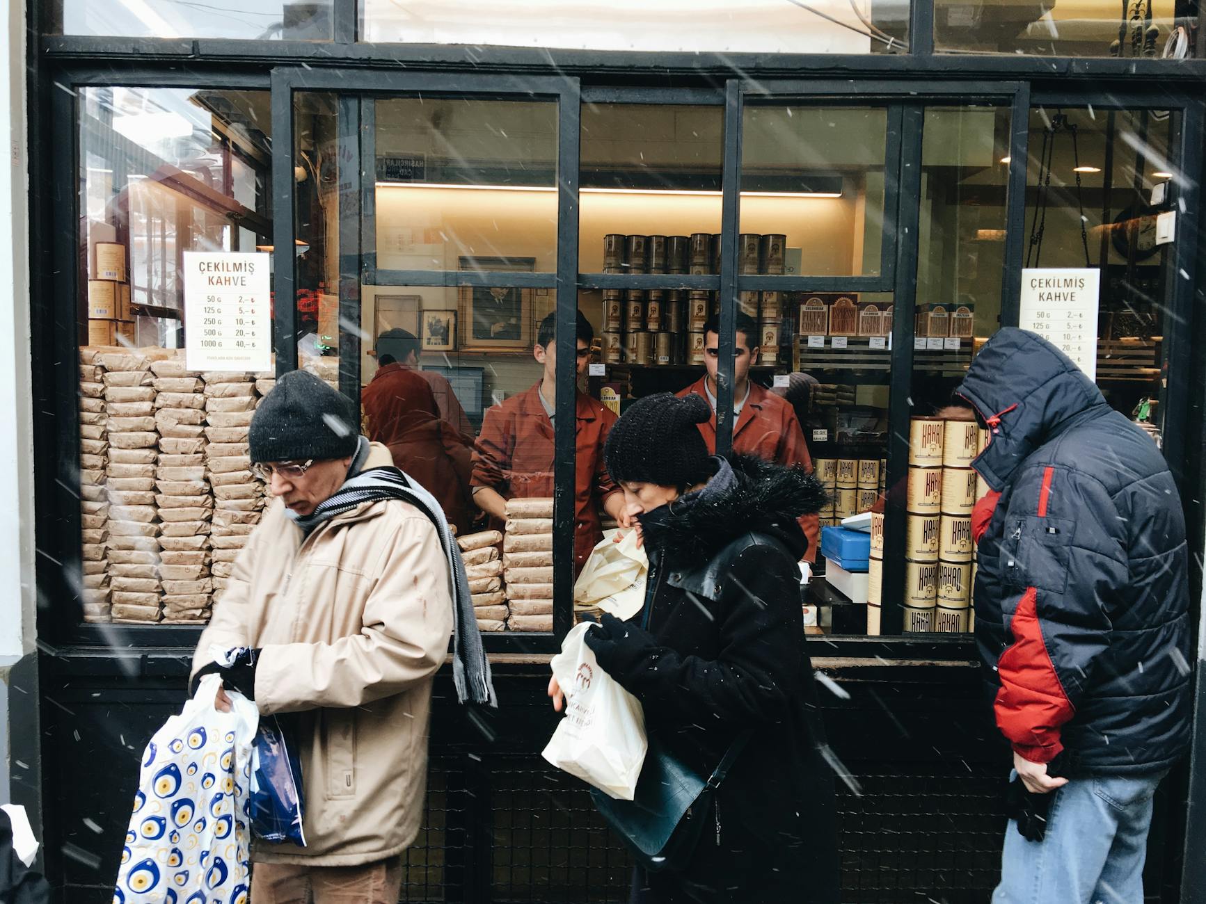 People purchasing coffee from a street vendor during a snowy day.