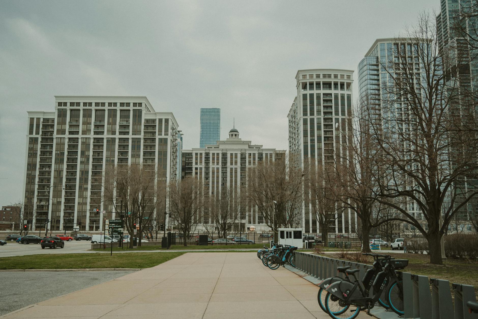 Bicycles lined up in front of apartment buildings in Chicago on a cloudy day.